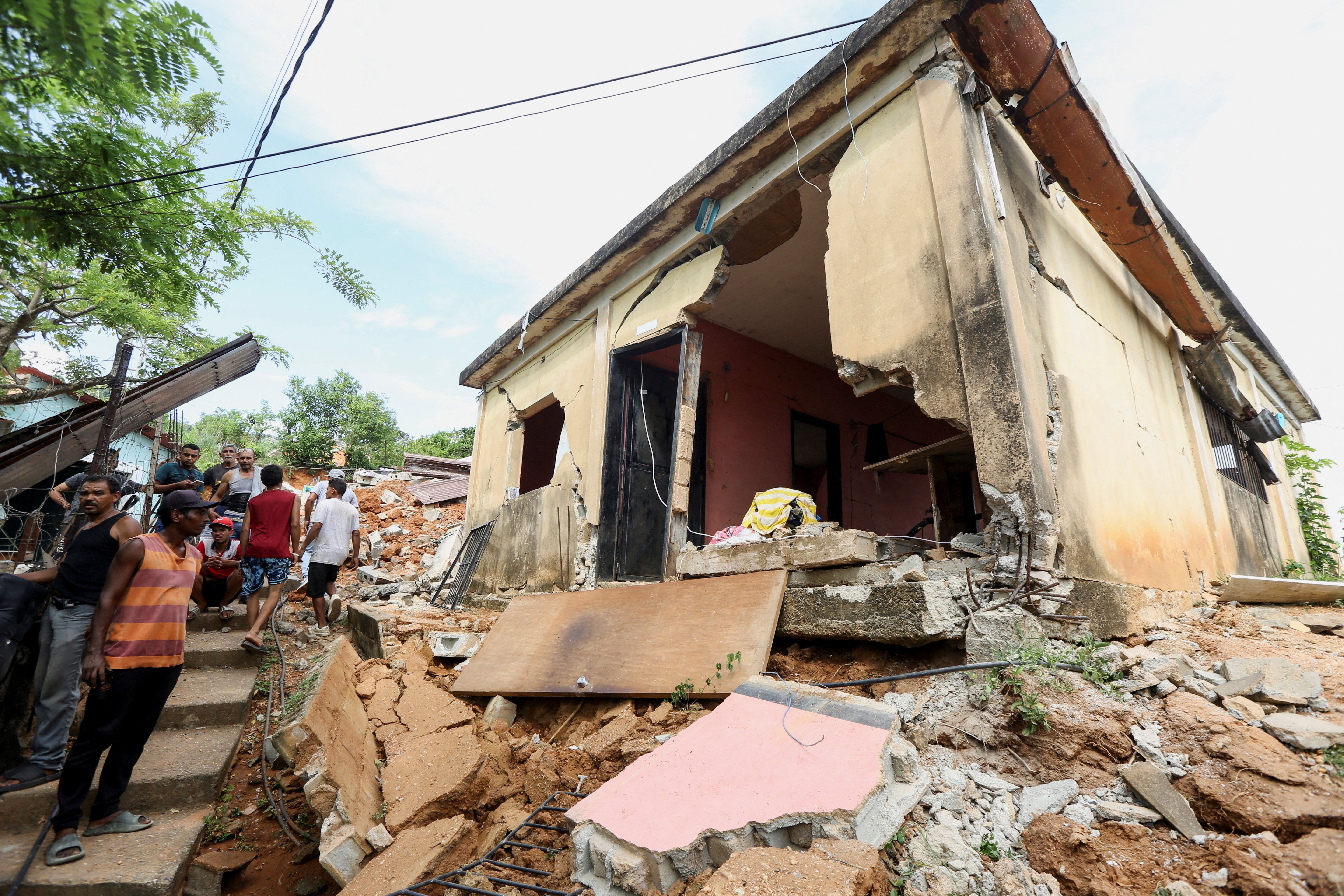 People stand near a house after an earthquake in Venezuela 