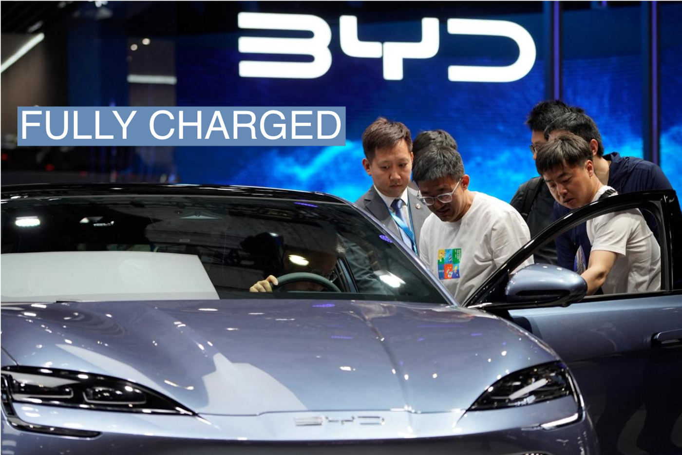 Attendees of the Shanghai Auto Show look at the specs of a BYD electric vehicle.
