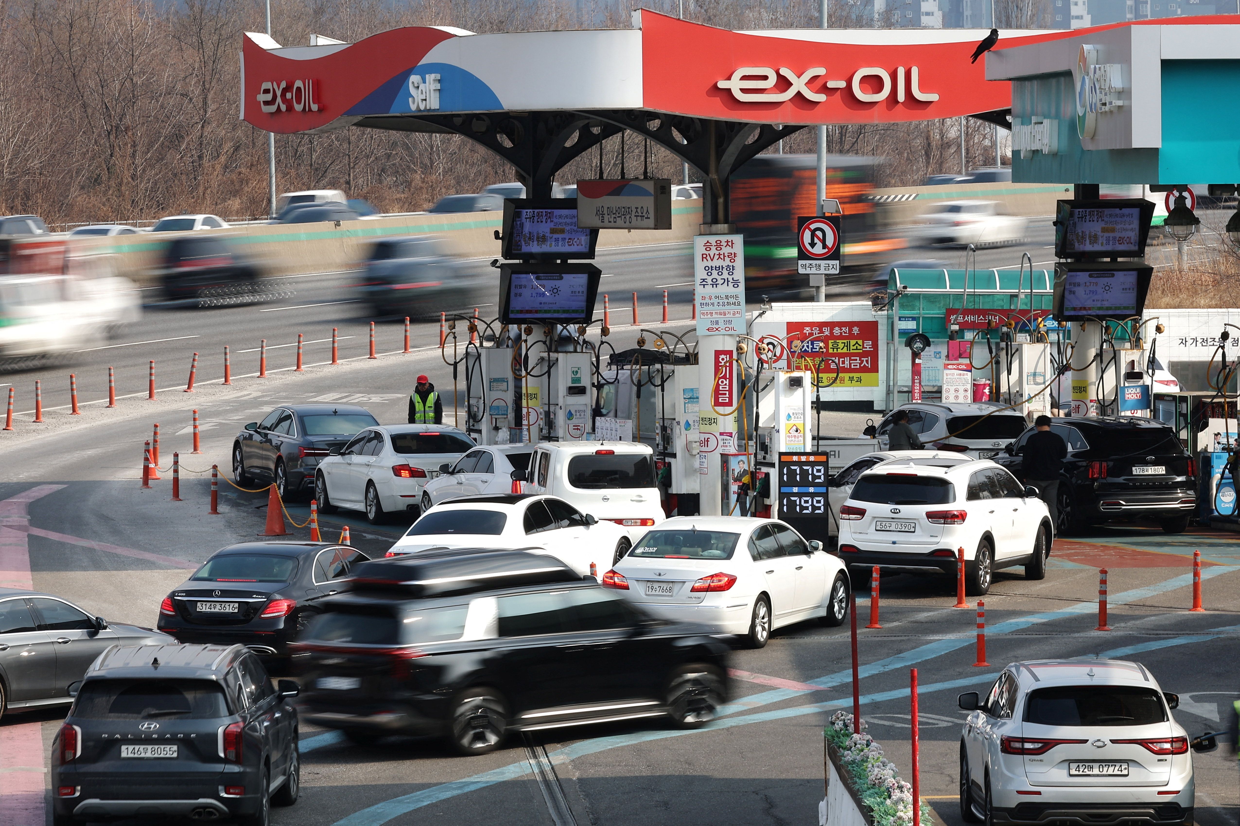 People fill up their car at a gas station in Seoul.
