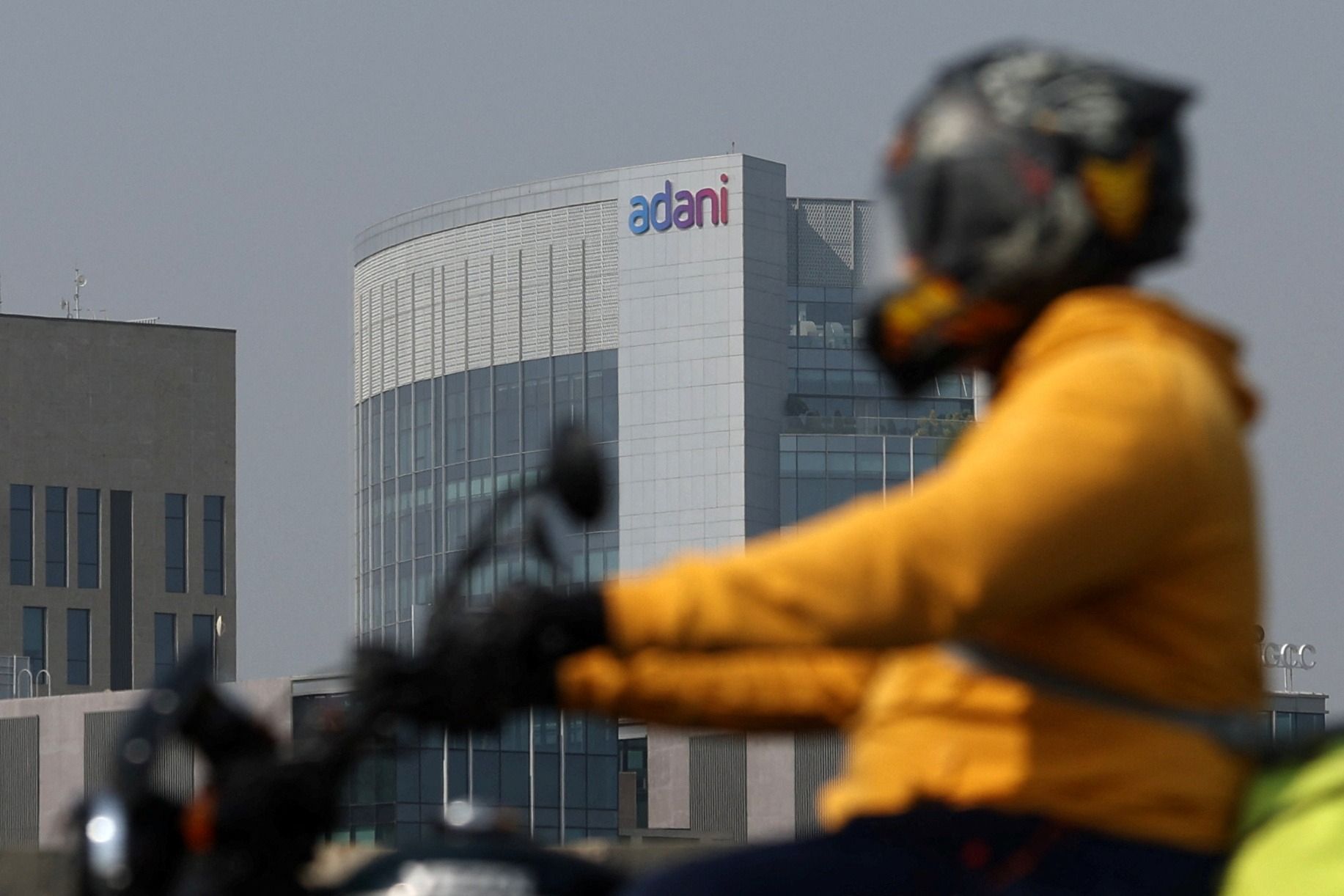 A man rides his motorbike past the Corporate House of Adani Group on the outskirts of Ahmedabad, India.