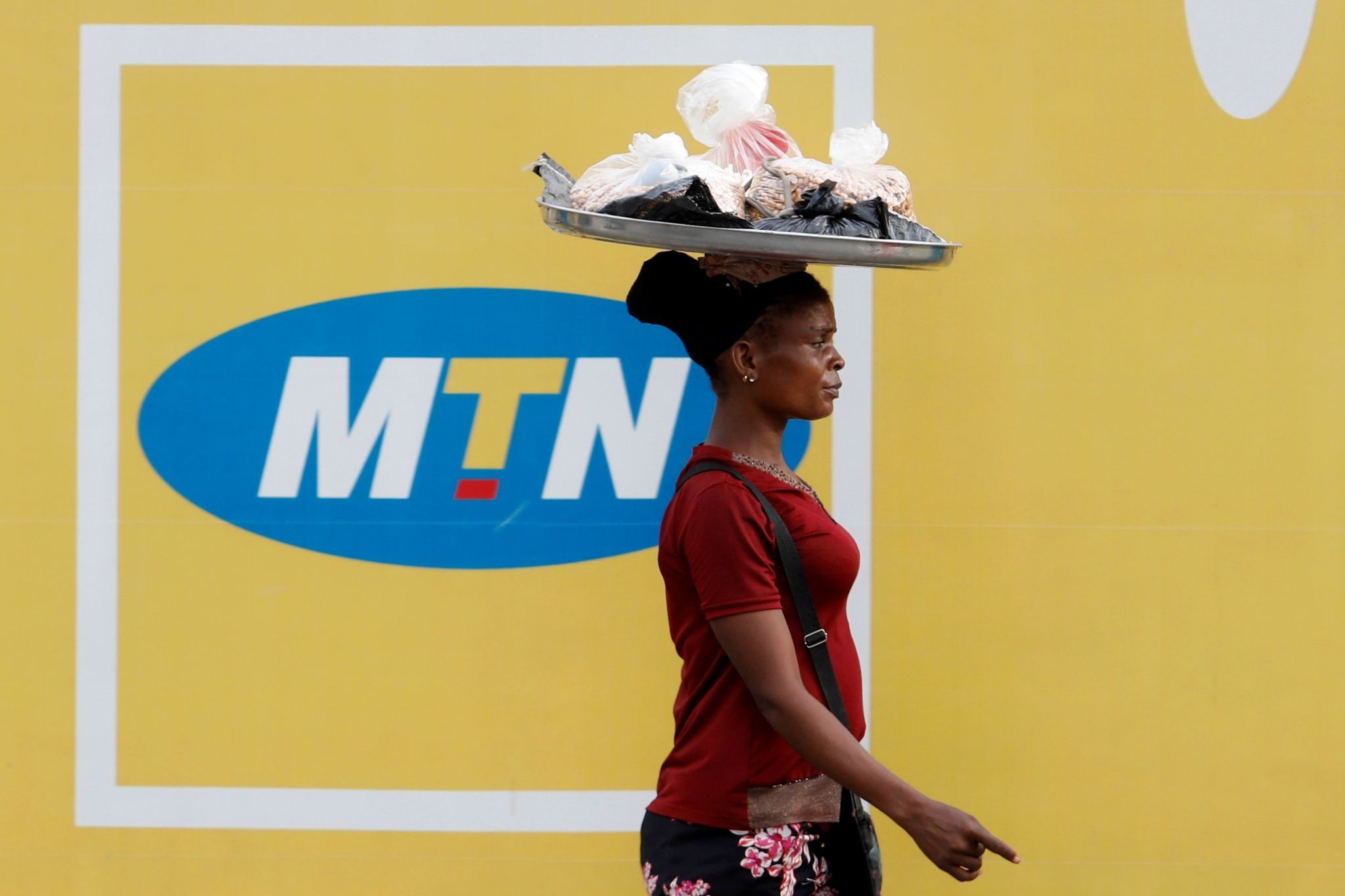 A woman walks past a poster advertising the MTN telecommunication company on a street in Lagos.