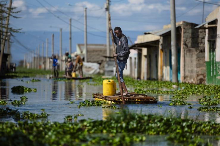 Residents use push poles to manuever makeshift rafts over a flooded road in Naivasha.