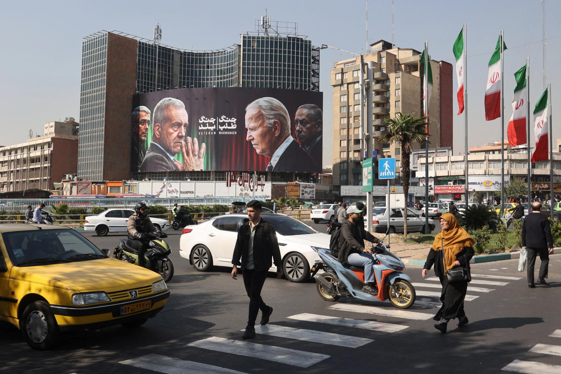 Iranians walk next to an anti-US and Israel billboard in Tehran.