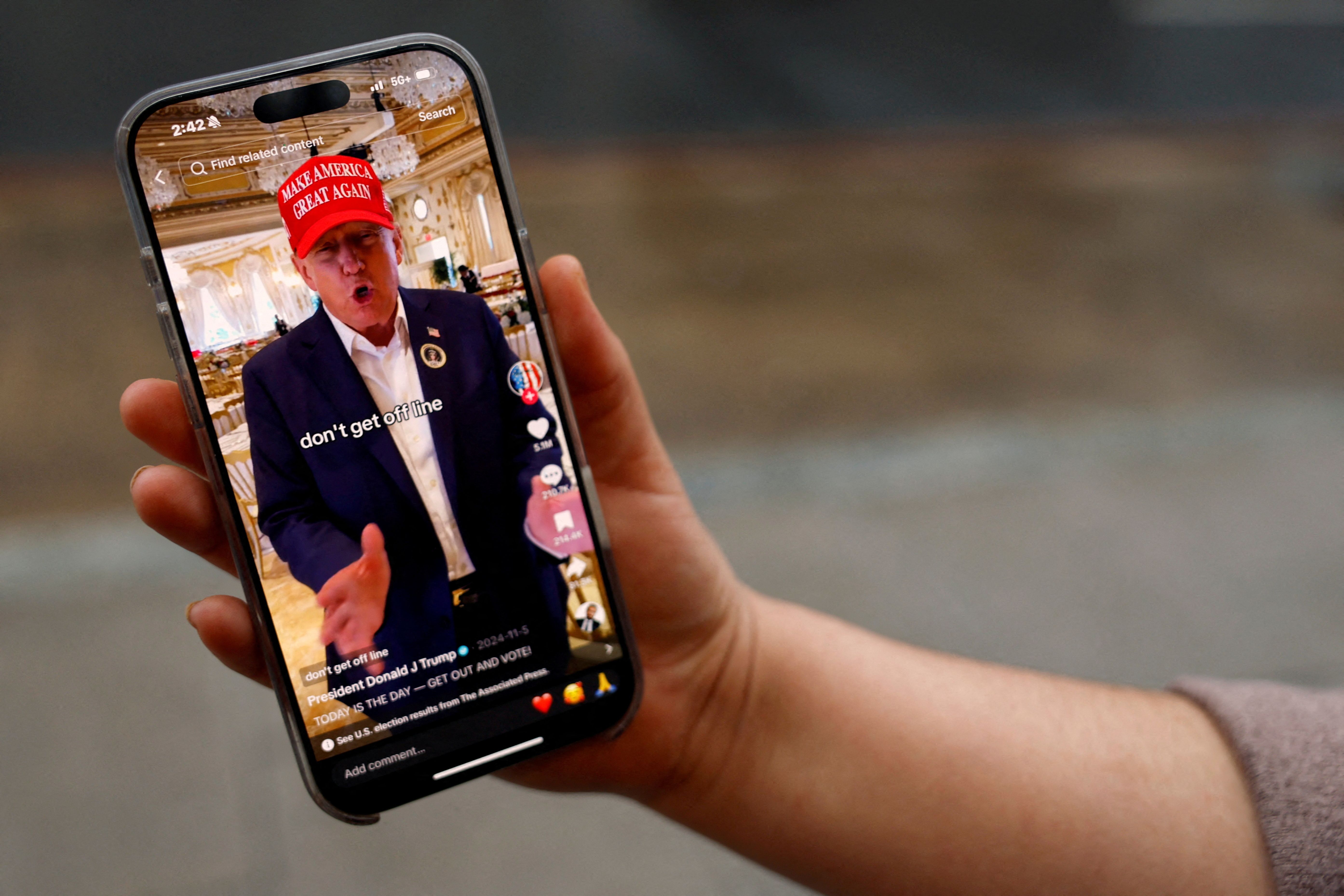 A woman poses with her smartphone displaying the @realdonaldtrump TikTok page, in Washington.