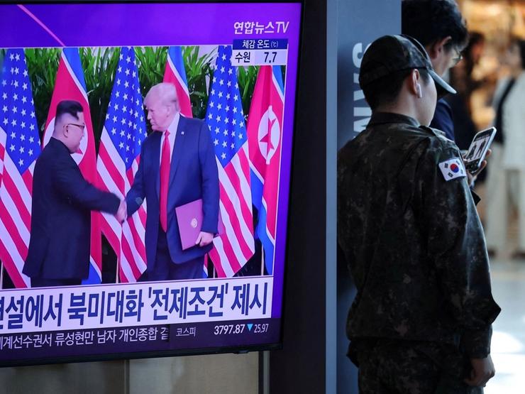 US President Donald Trump shakes hands with North Korean Leader Kim Jong Un on TV