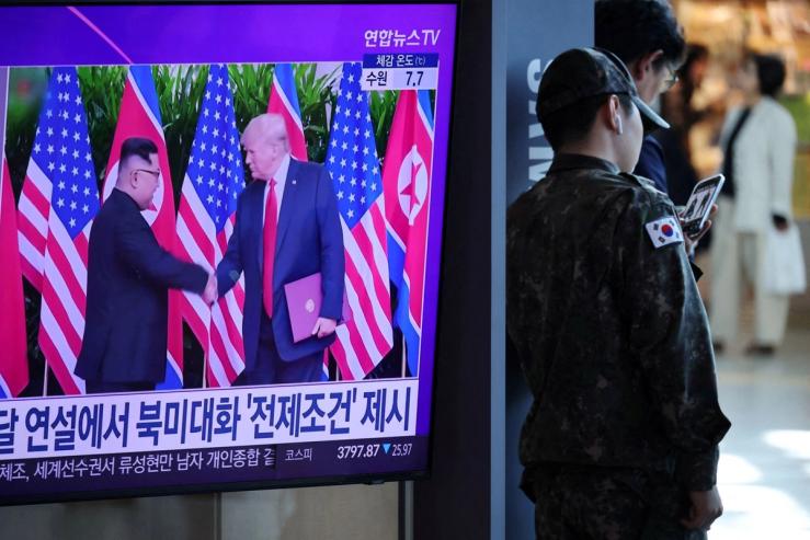 US President Donald Trump shakes hands with North Korean Leader Kim Jong Un on TV