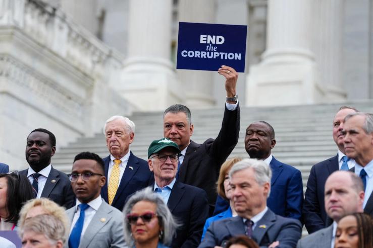 U.S. Senator Alex Padilla (D-CA) holds a sign reading, “End the Corruption” during a news conference ahead of voting on the Senate immigration funding bill on Capitol Hill in Washington, D.C., U.S.