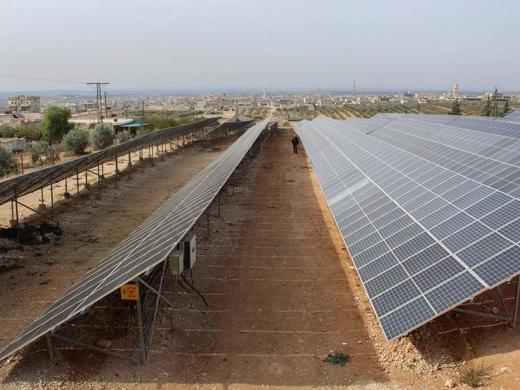 A worker walks inside a solar farm in Syria
