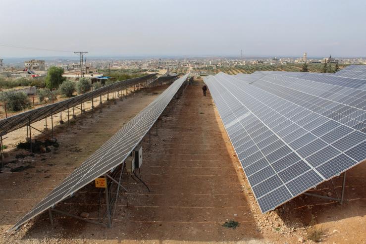 A worker walks inside a solar farm in Syria
