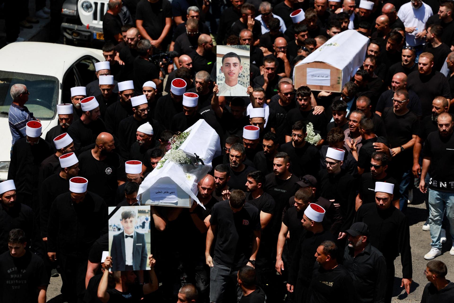 Mourners carry coffins during the funeral of children killed at a soccer pitch. 