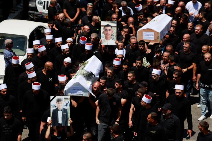 Mourners carry coffins during the funeral of children killed at a soccer pitch.