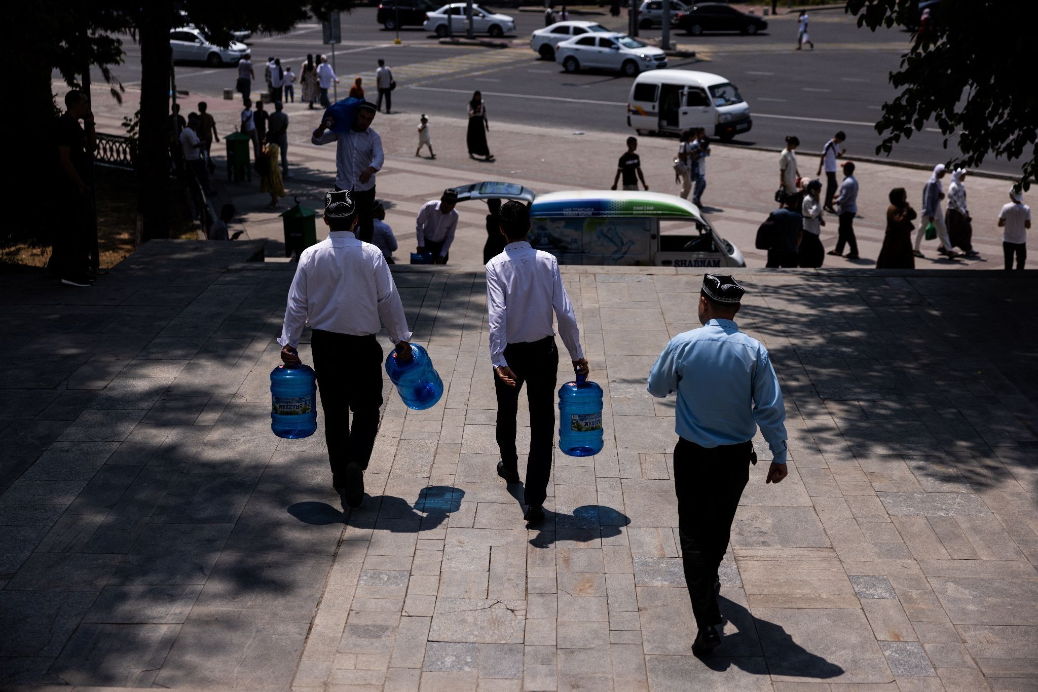 Men carry water cans in the street during a hot day in Tashkent