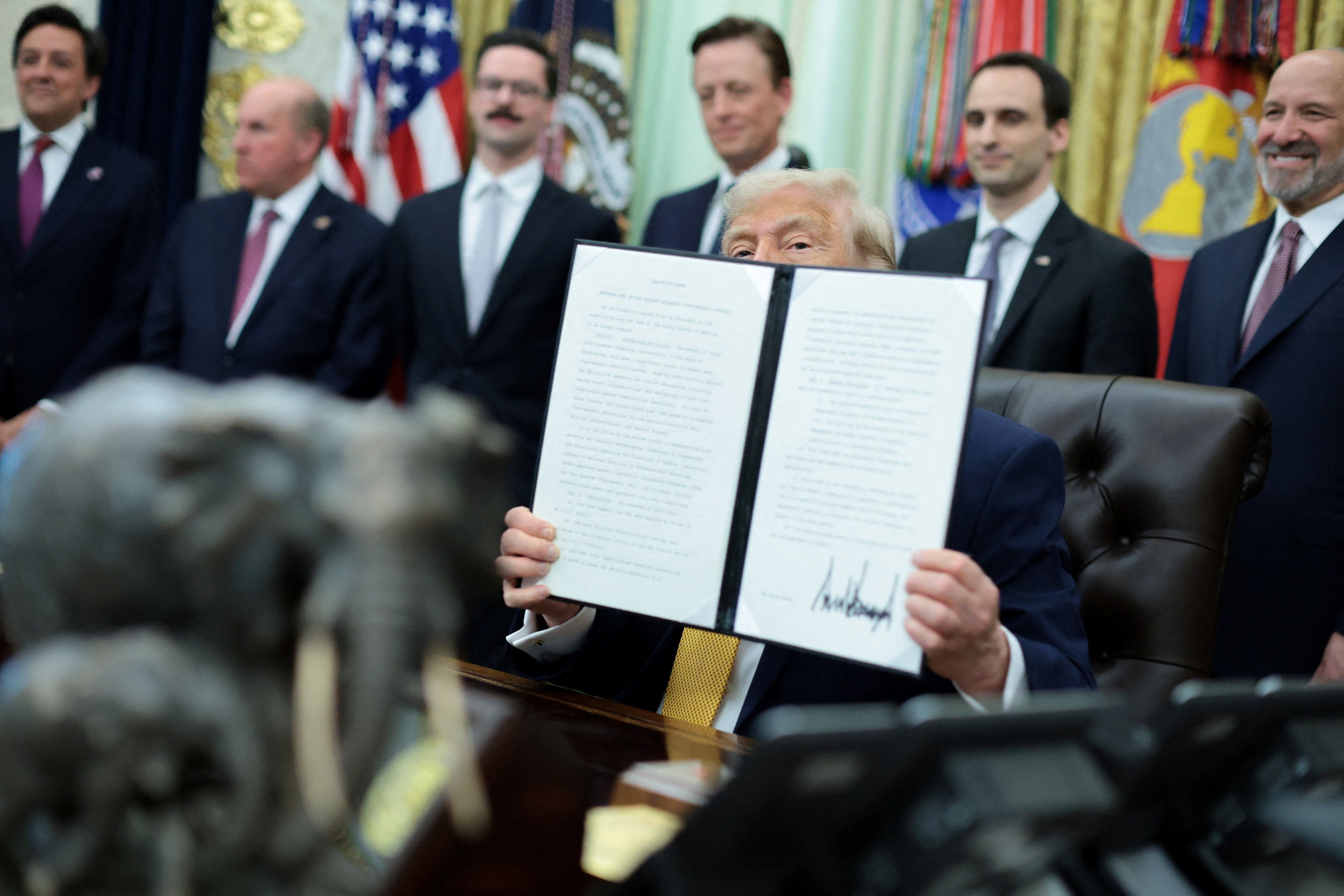 Donald Trump holds up a signed executive order