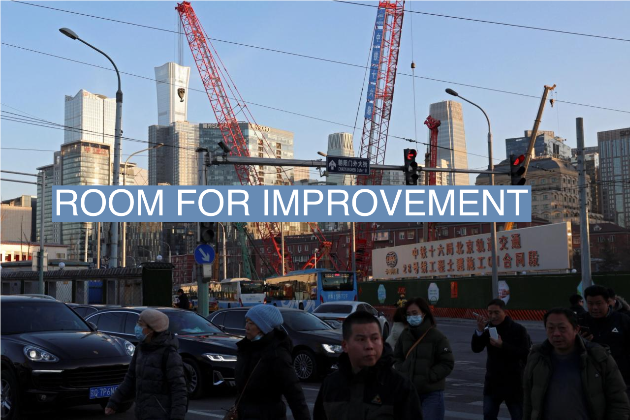 People cross an intersection near cranes standing at a construction site in Beijing, China January 15, 2024.