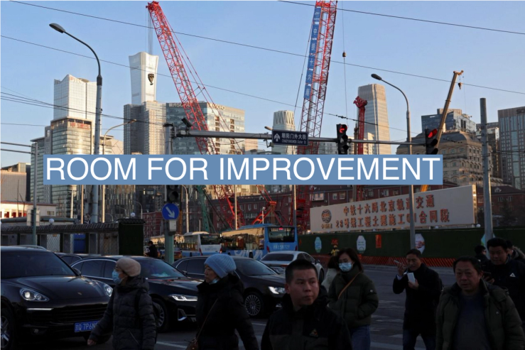 People cross an intersection near cranes standing at a construction site in Beijing, China January 15, 2024.