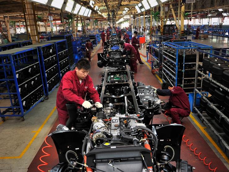 Workers install the chassis along a production line at a truck factory of Anhui Jianghuai Automobile Co. Ltd (JAC Motors) in Hefei, Anhui province May 5, 2014.