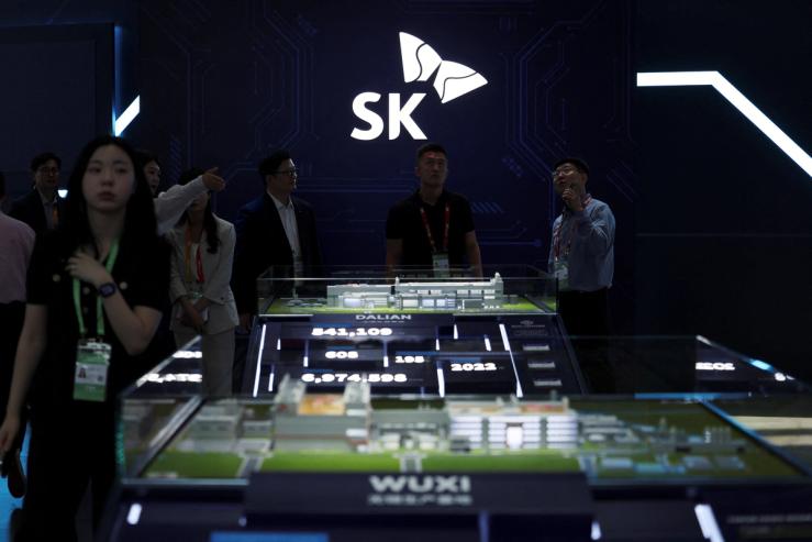 People stand near a logo of SK Hynix at the South Korean chipmaker’s booth during the China International Supply Chain Expo (CISCE) in Beijing