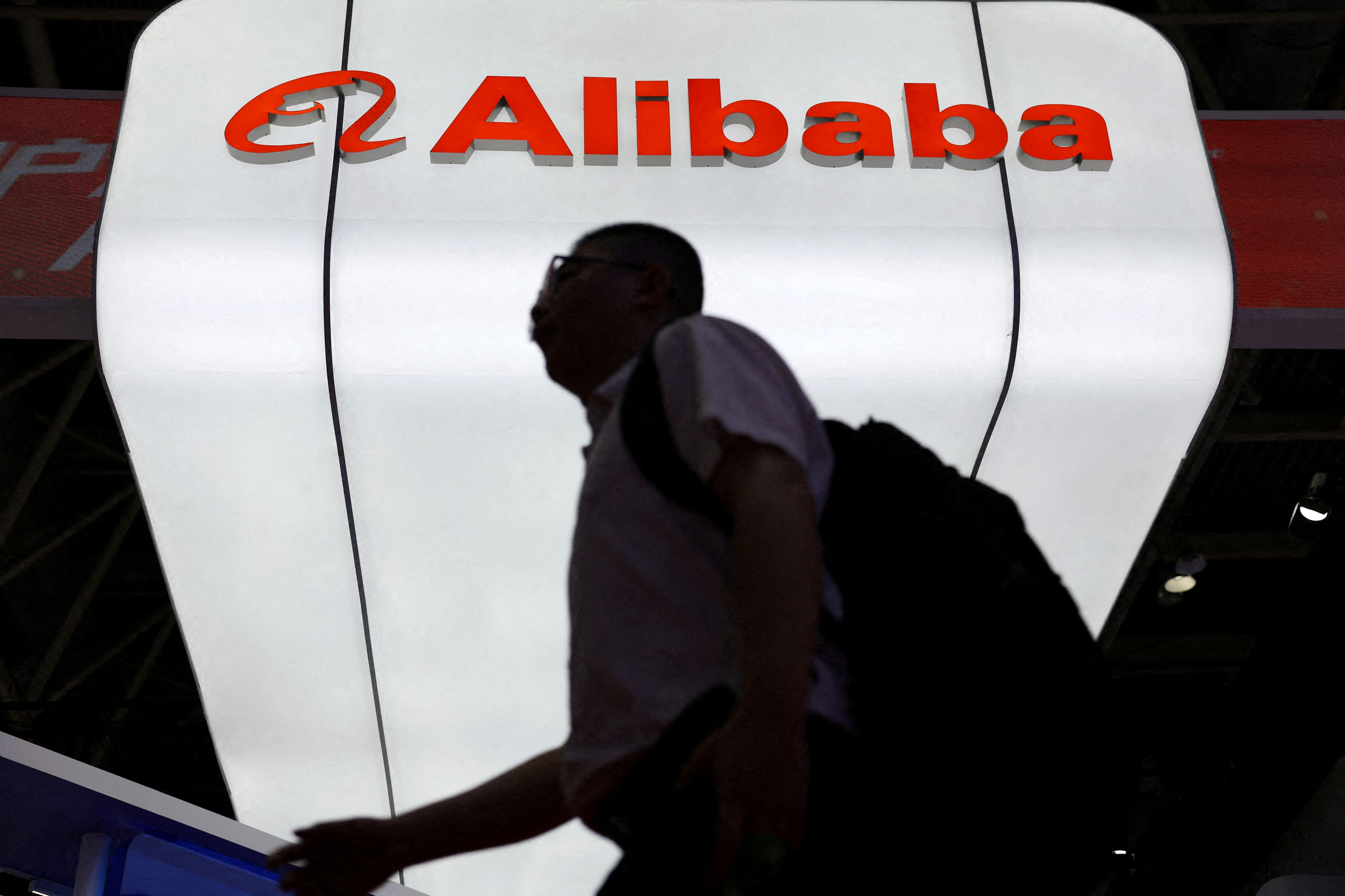 A man walks past the Alibaba logo displayed at its booth during the China International Supply Chain Expo.