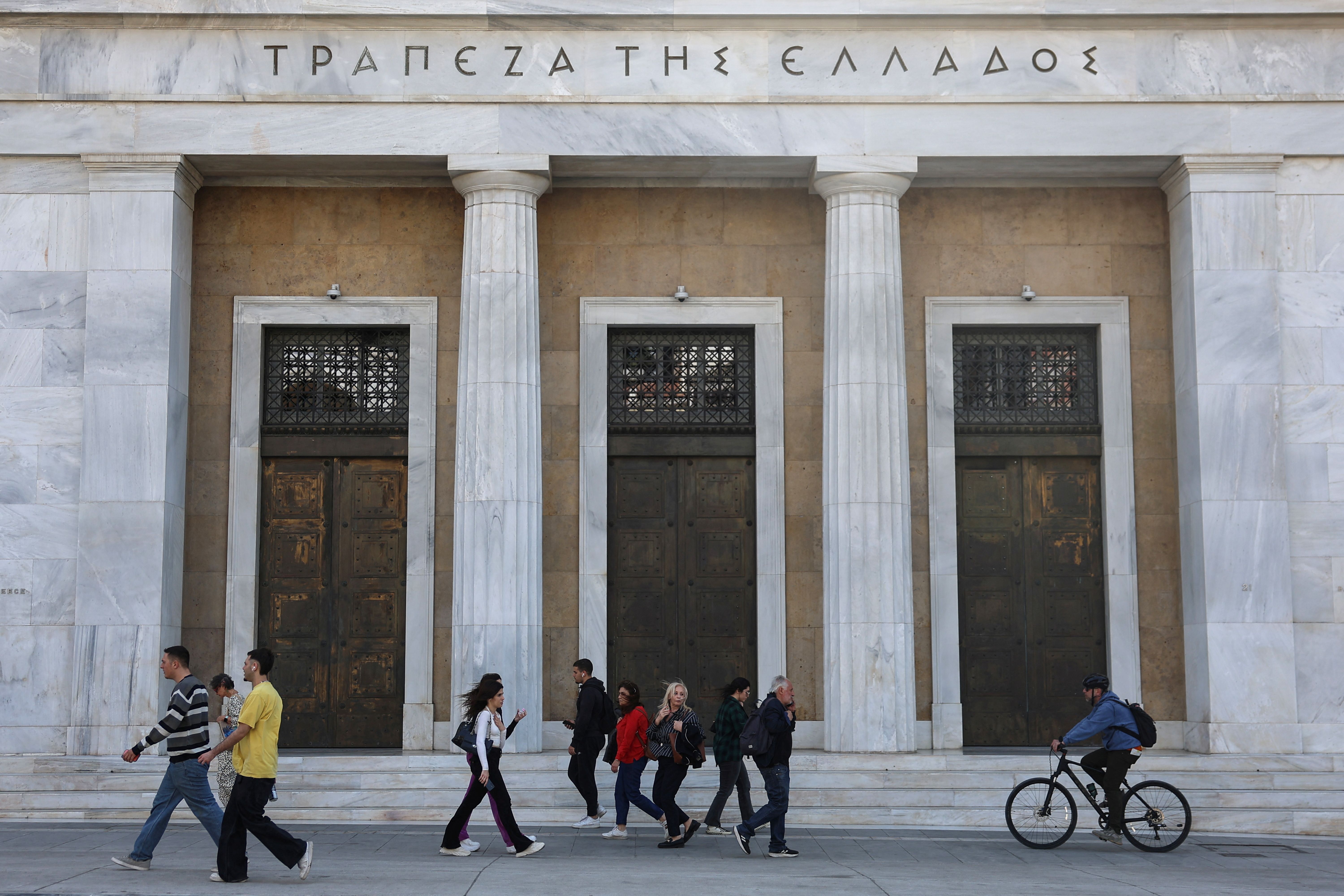 People walk in front of Bank of Greece in central Athens.