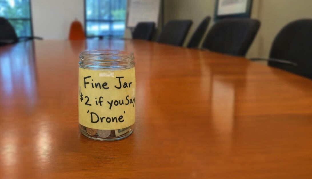 Picture of swear jar with the words “$2 if you say ‘drone’” 
