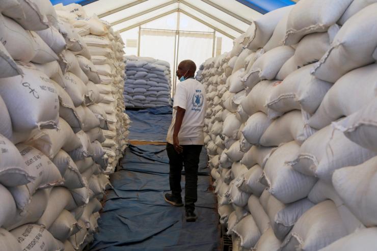 World Food Programme employee walks between sacks of food at the Um Rakuba refugee camp which houses Ethiopian refugees.