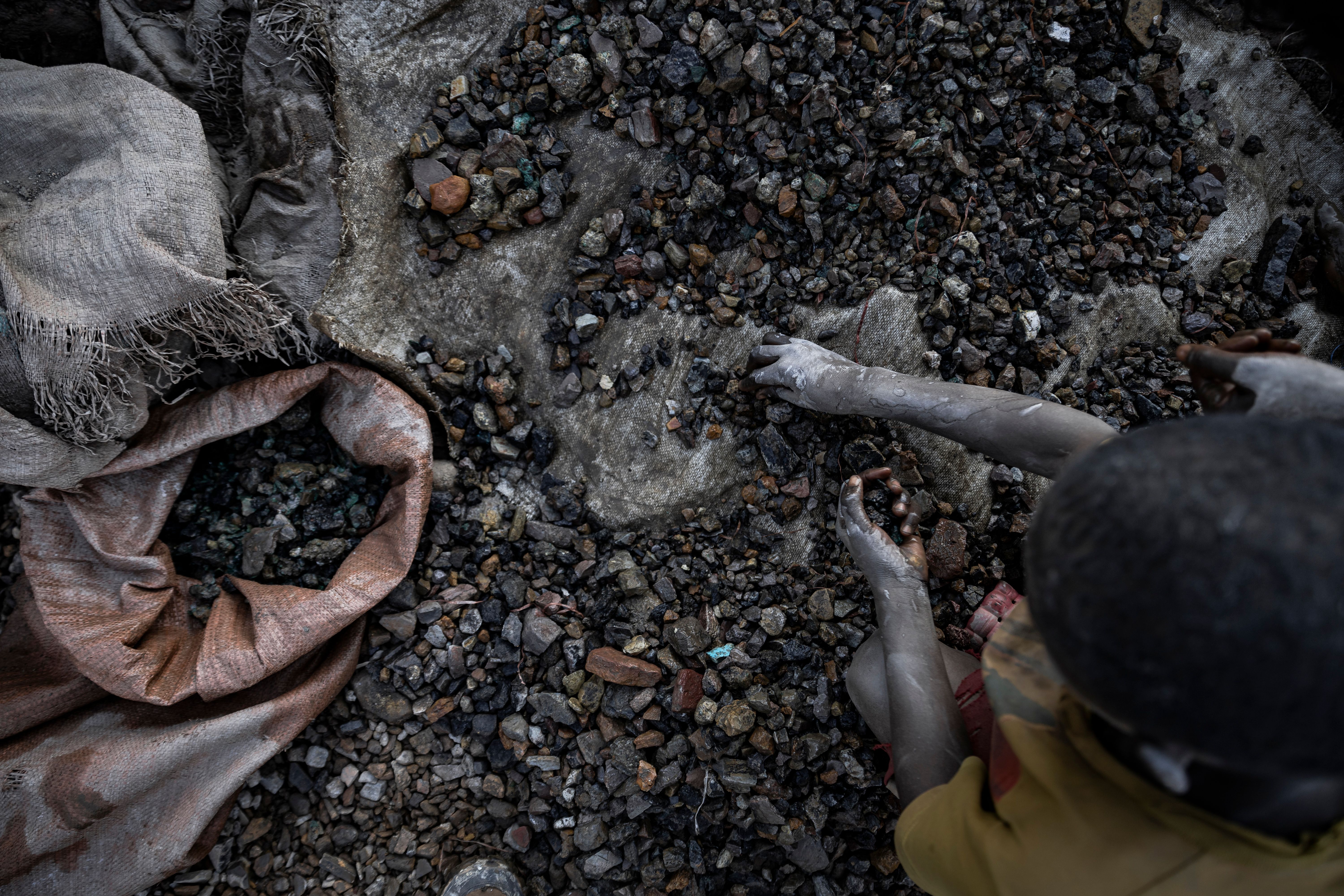  A young person sifts through stones at a cobalt and copper mining pit .
