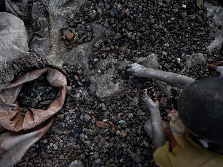 A young person sifts through stones at a cobalt and copper mining pit .