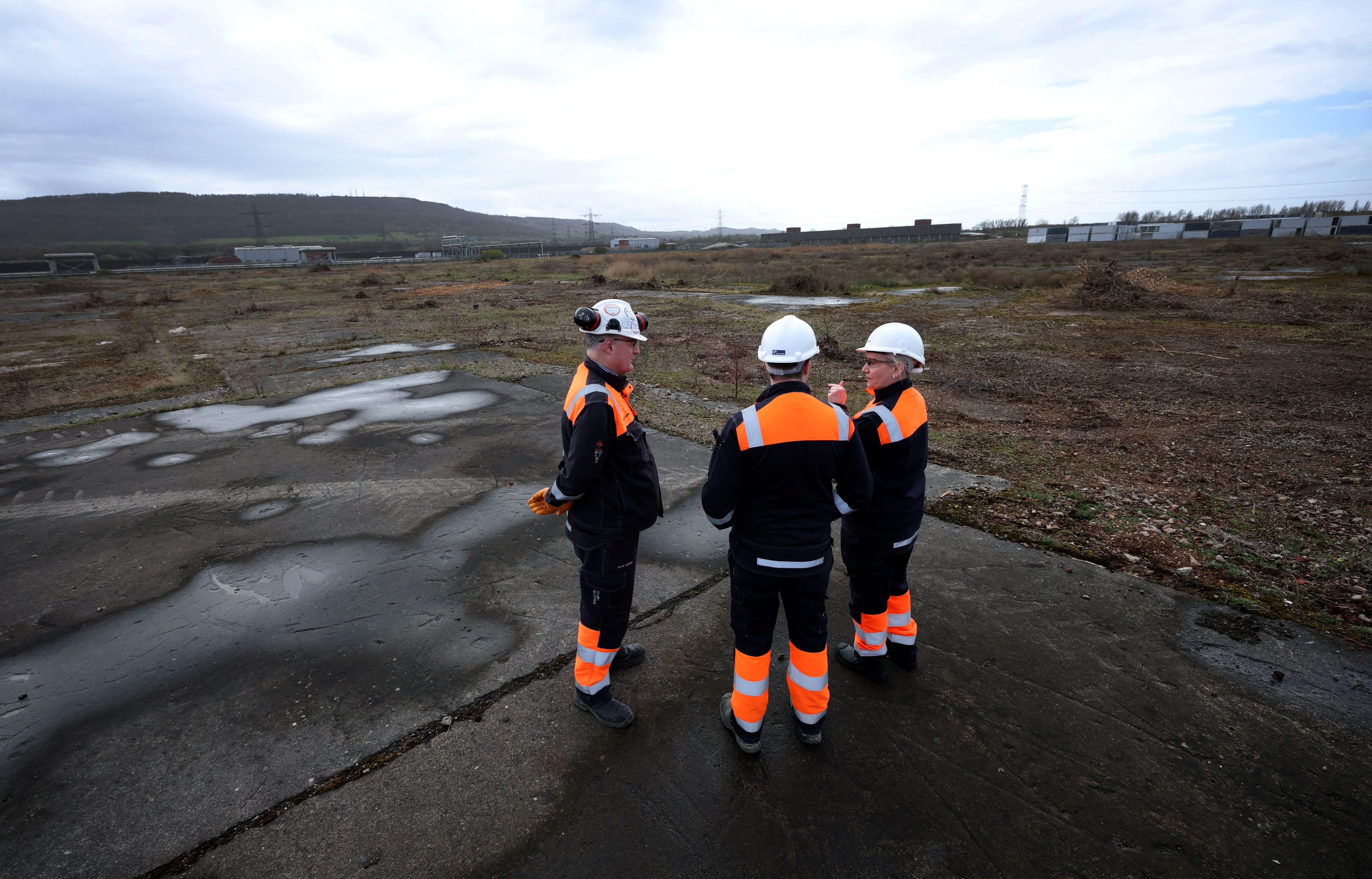 Sembcorp employees stand on a patch of disused land earmarked as a future site for a data center on the Wilton International site near Middlesbrough, Britain