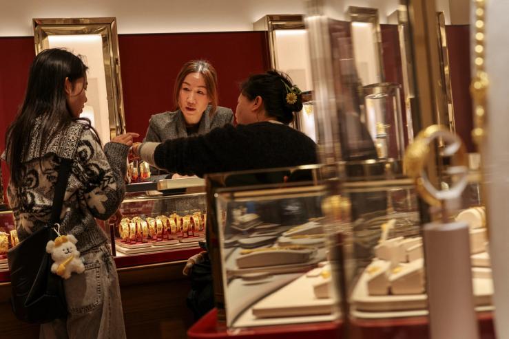 A customer tries a gold bracelet inside a jewellery store, in Hong Kong.