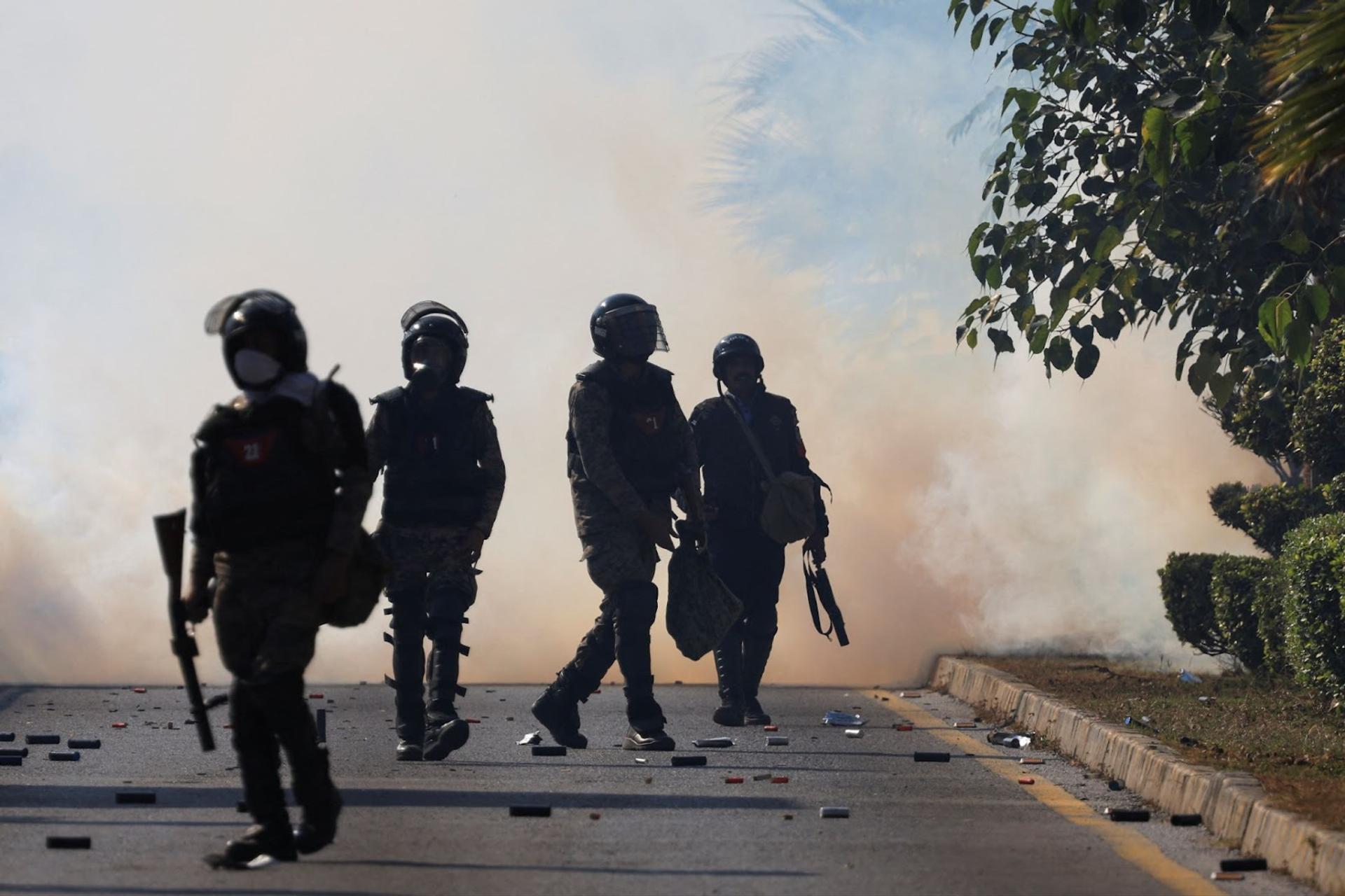 Security force personnel walk as smoke billows from tear gas shells fired to prevent an anti-government protest by supporters of the former Pakistani Prime Minister Imran Khan’s party Pakistan Tehreek-e-Insaf (PTI) demanding the release of Khan, in Islamabad, Pakistan.