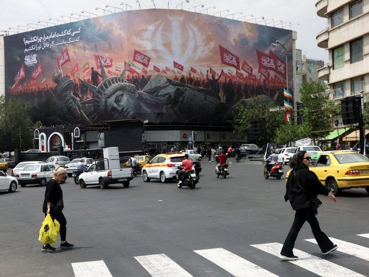 People walk past an anti-U.S. billboard on a street in Tehran, Iran.