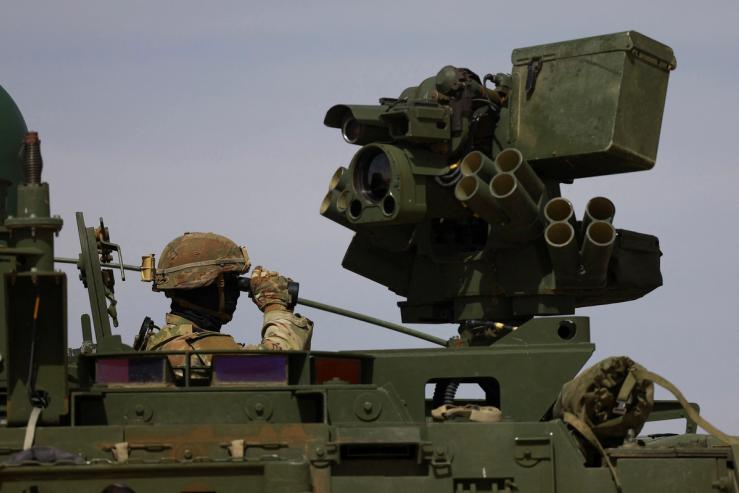 A US Army member looks through binoculars aboard an armored vehicle at the US-Mexico border.