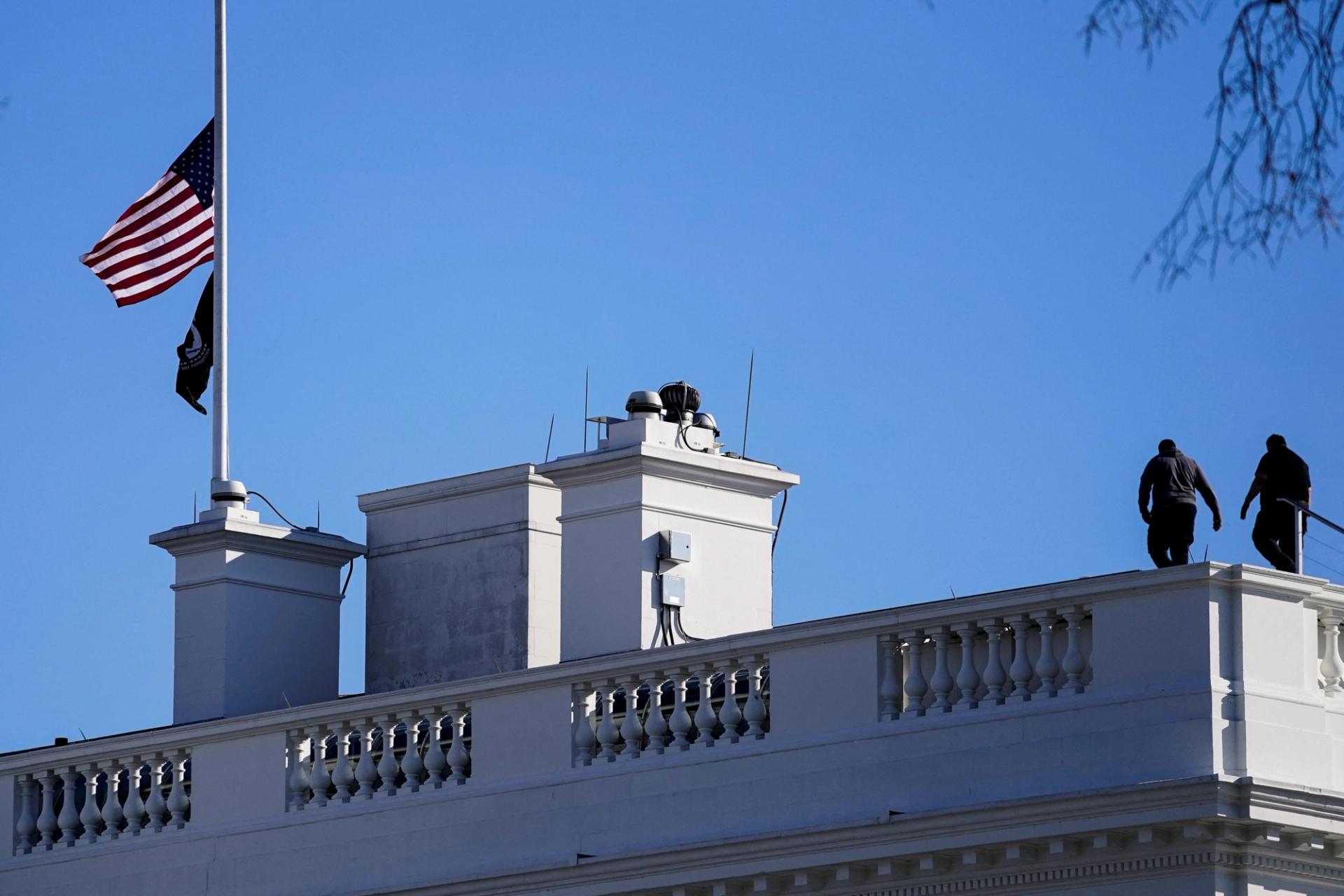 Workers walk on the roof of the White House