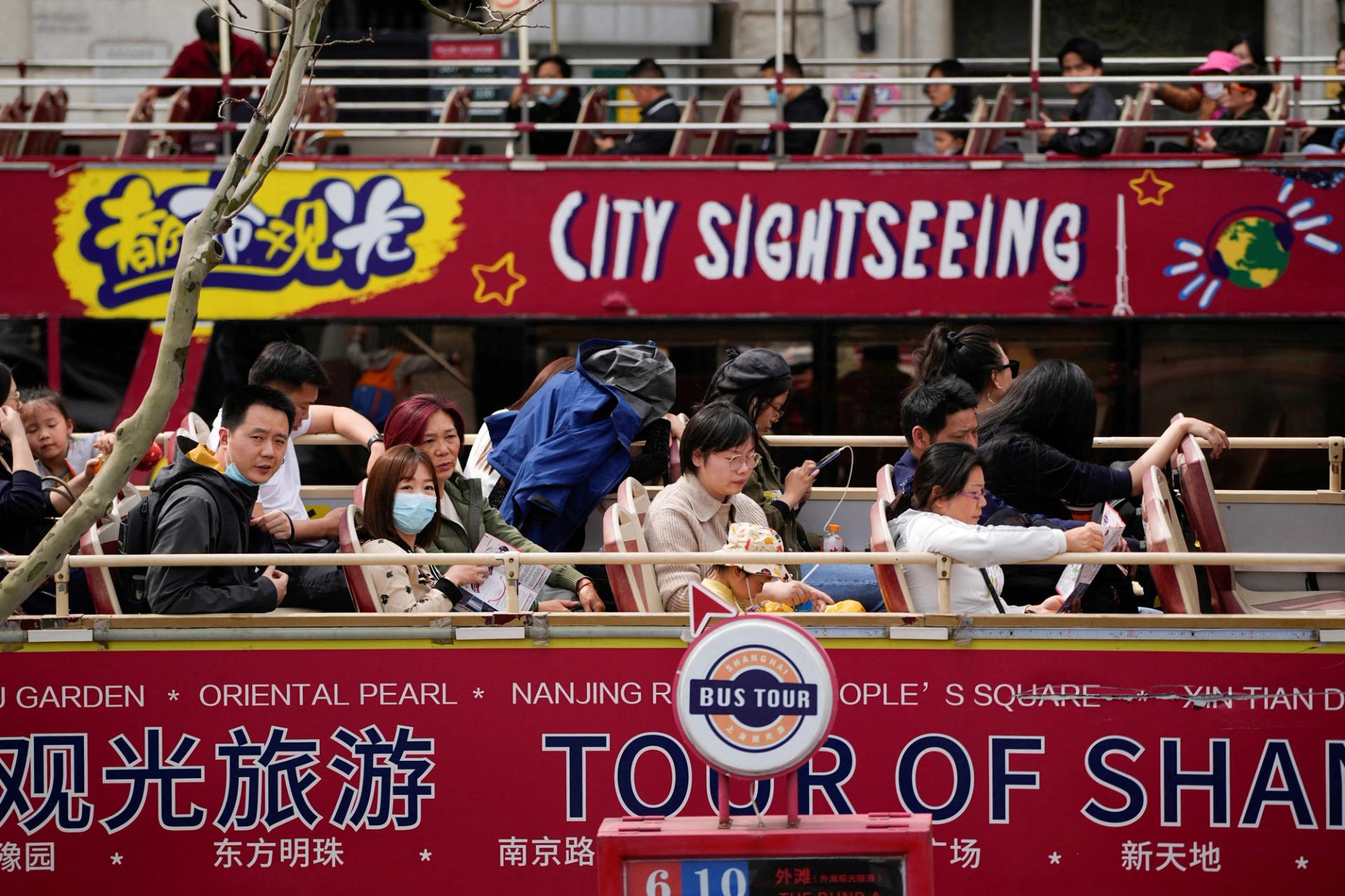 Tourists ride on a tourist double-decker bus in Shanghai, China.