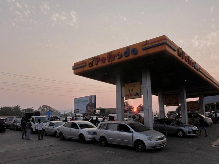Cars queue at a fueling station.