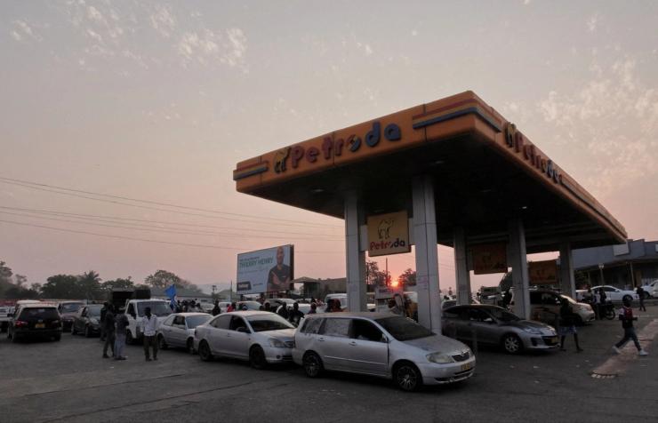 Cars queue at a fueling station.