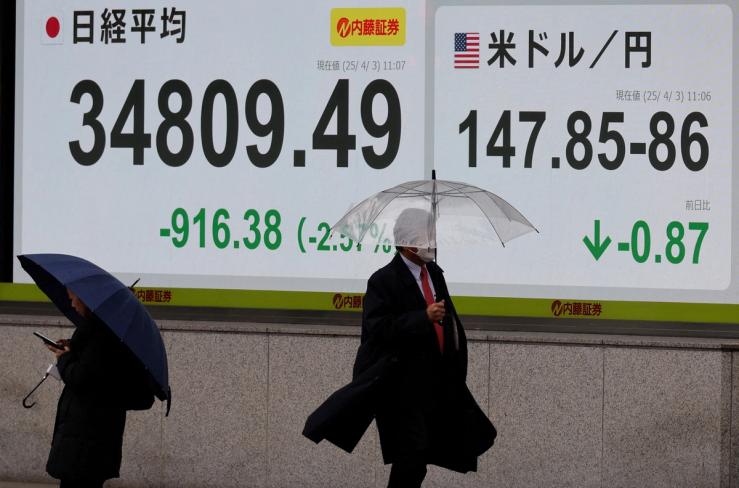 Pedestrians walk past a stock quotation board showing Nikkei share average and exchange rate between Japanese yen and U.S. dollar outside a brokerage in Tokyo.