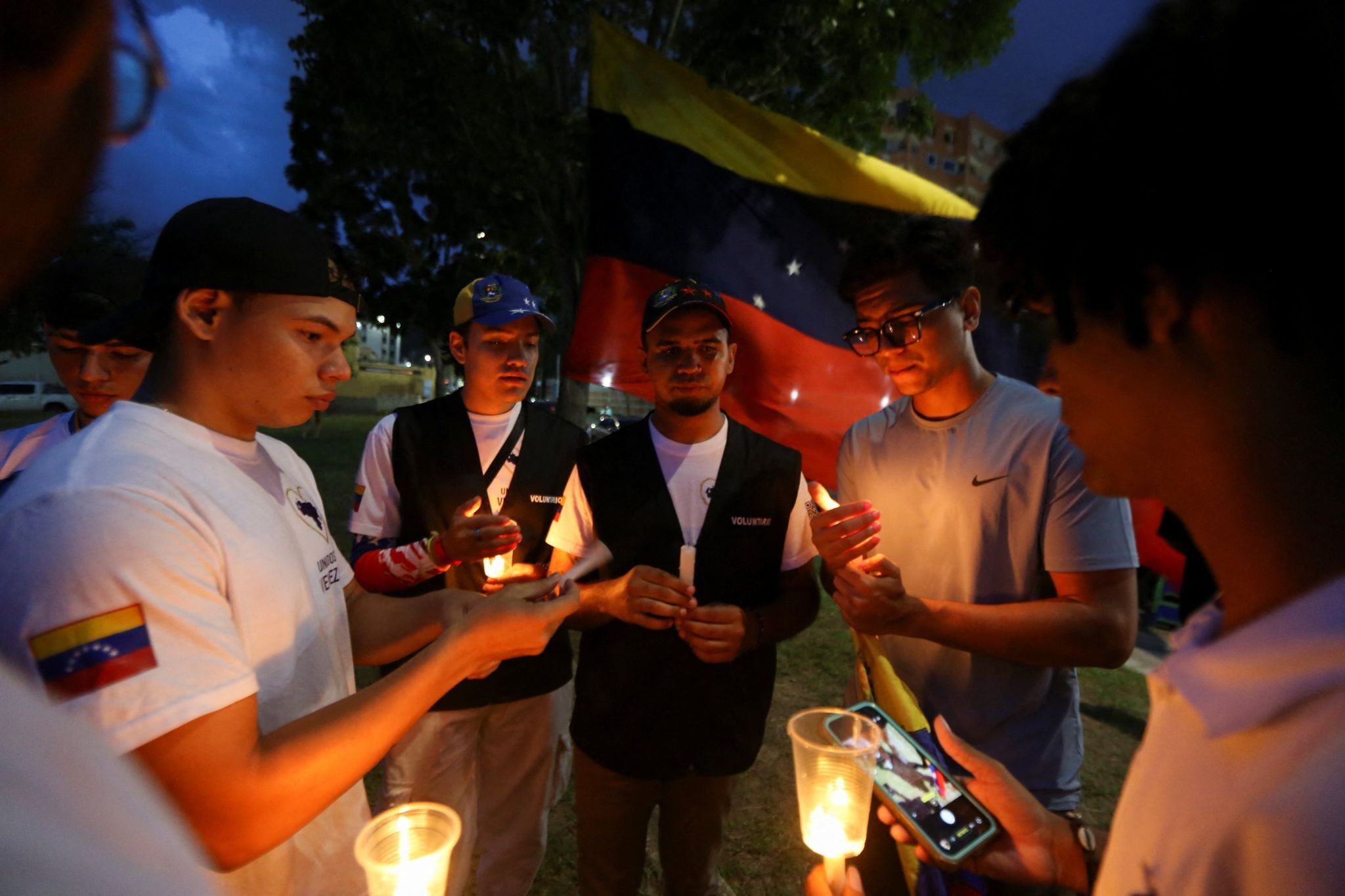 People hold candles during a vigil for people affected by the earthquakes