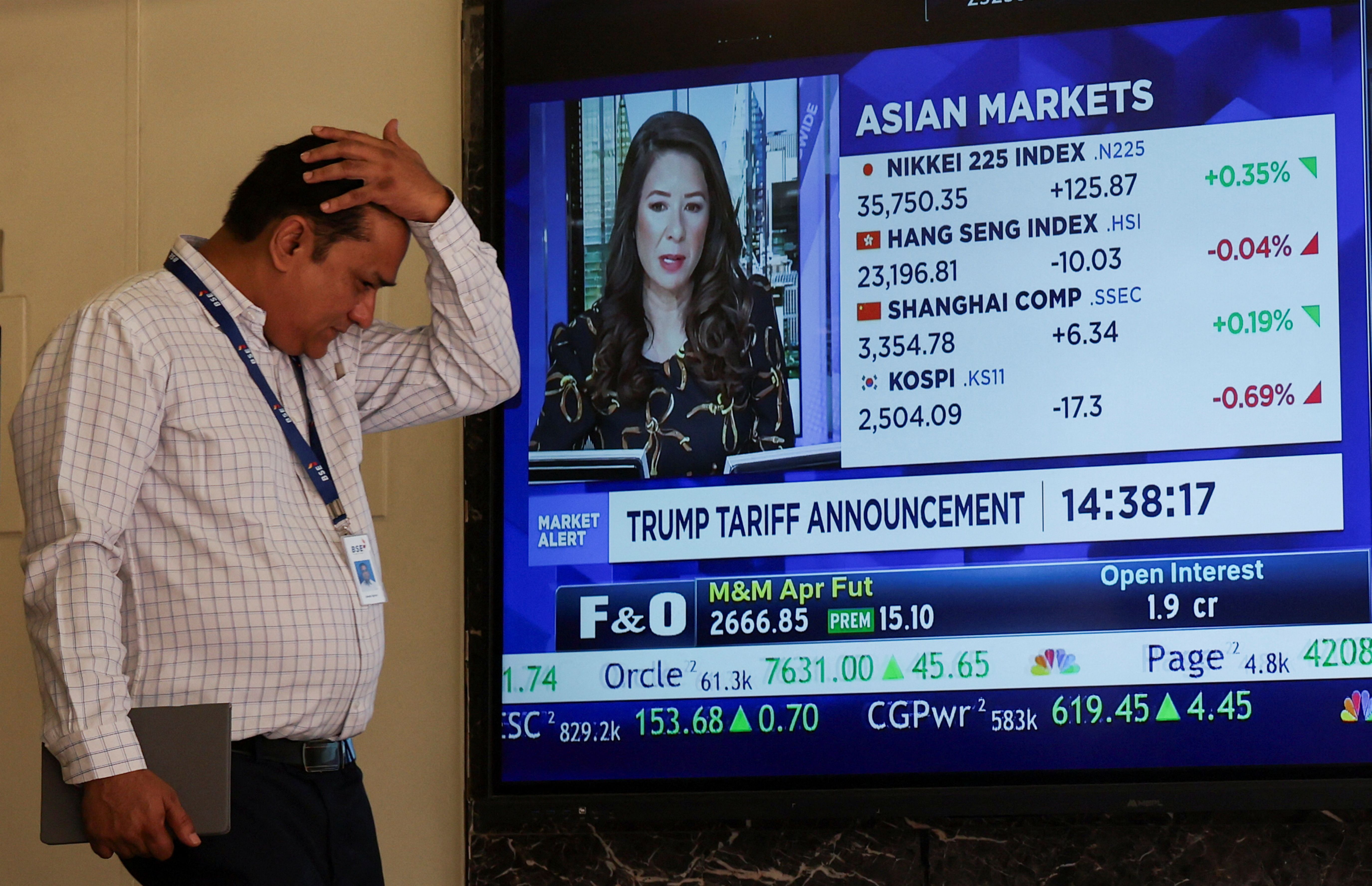 A man walks past a screen at the Bombay Stock Exchange.