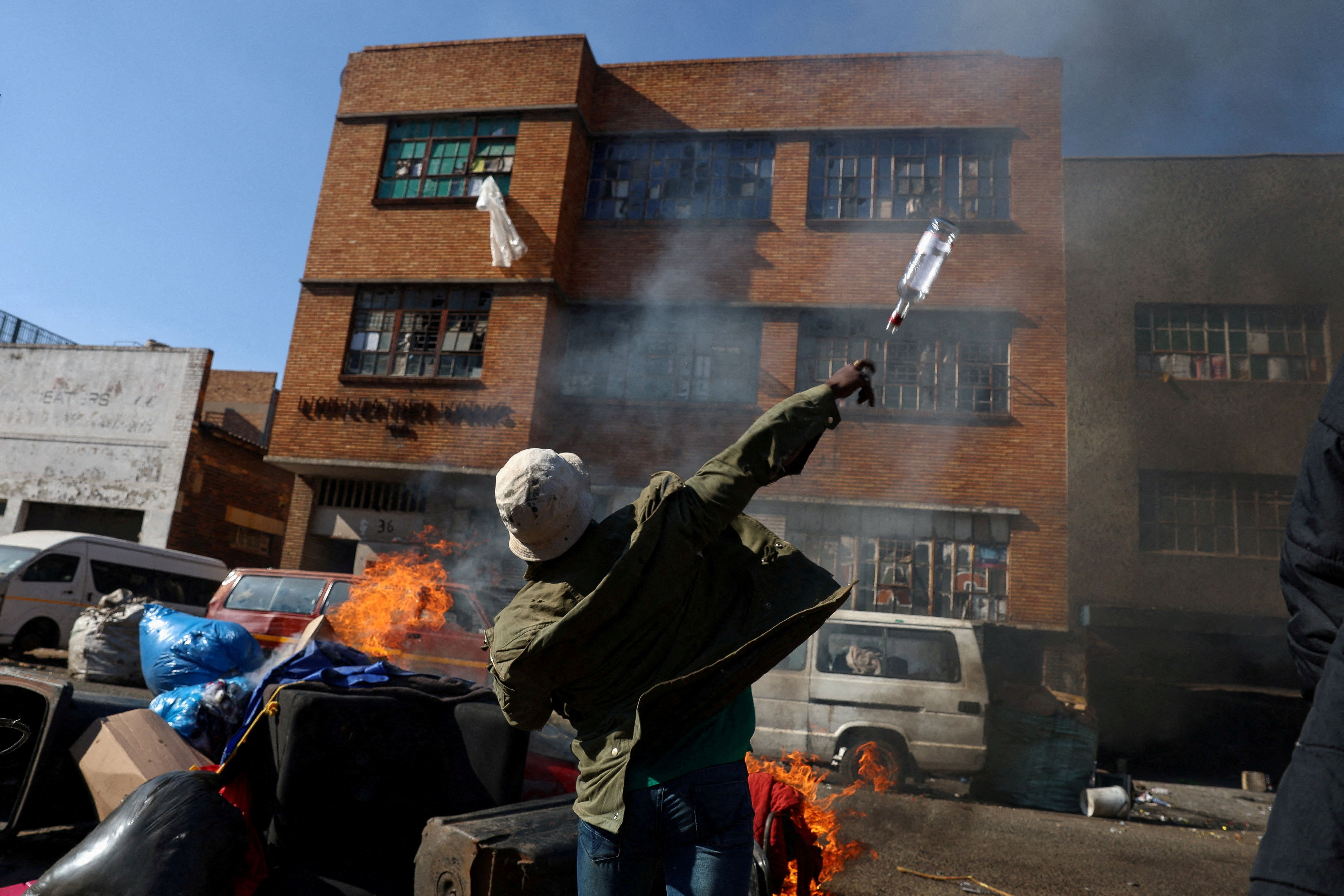An anti-immigrant demonstrator throws a bottle at a building in Johannesburg.