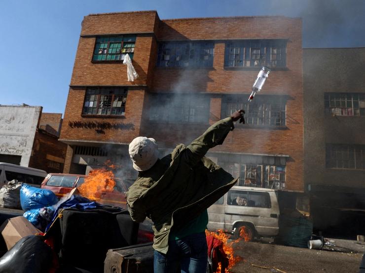 An anti-immigrant demonstrator throws a bottle at a building in Johannesburg.