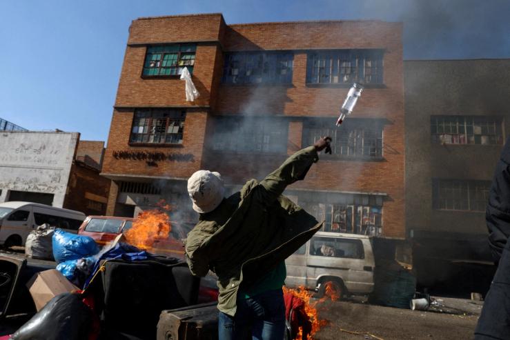 An anti-immigrant demonstrator throws a bottle at a building in Johannesburg.