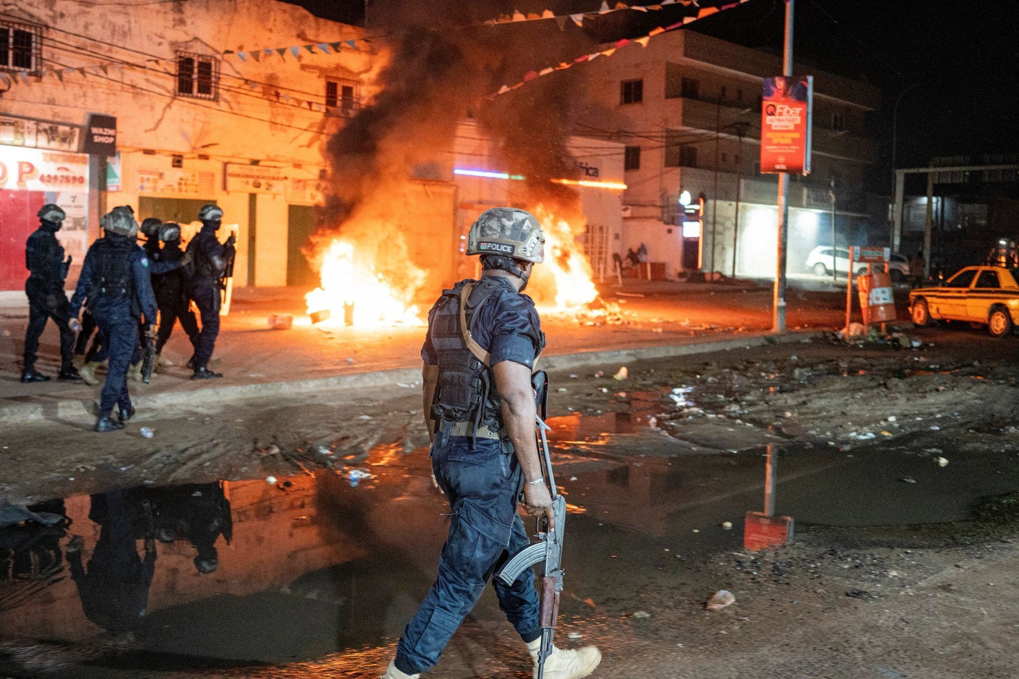 Police officers patrol near burning barricades as residents protest against power and water cuts in Banjul, Gambia, September 8, 2026.