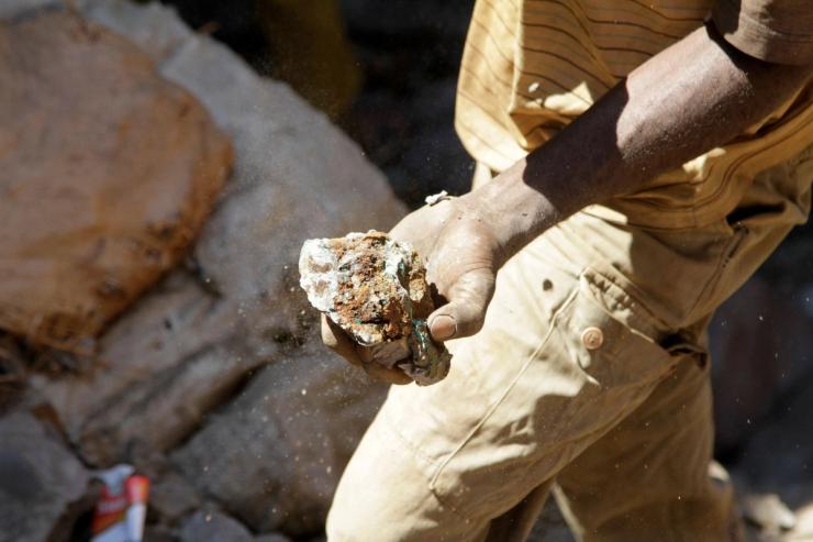 An artisanal miner carries raw ore at a former industrial copper-cobalt mine, outside of Kolwezi, in southern DR Congo.