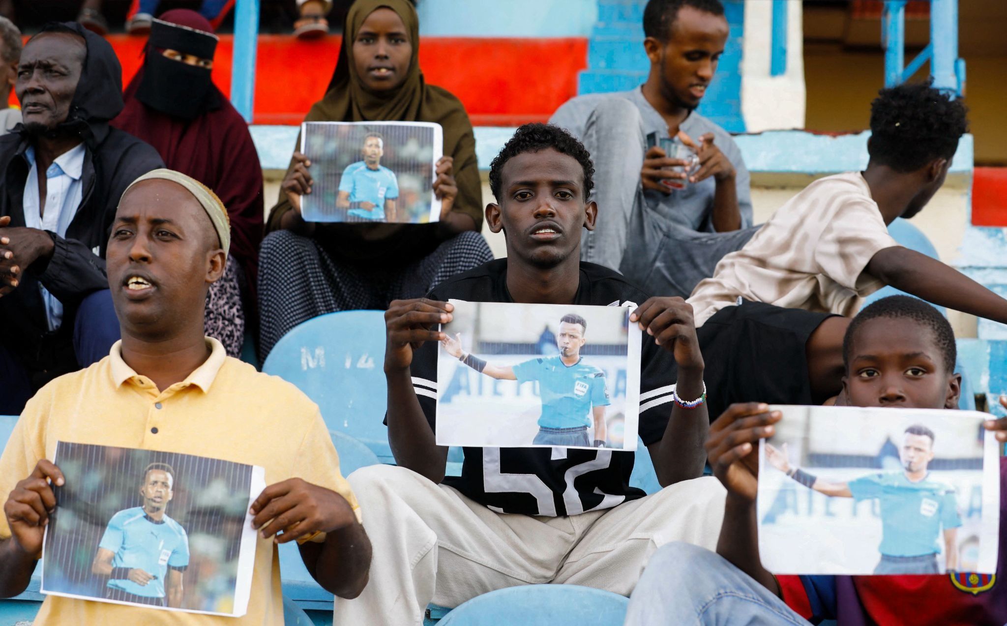 Somalis hold pictures of referee Omar Abdulkadir Artan. 