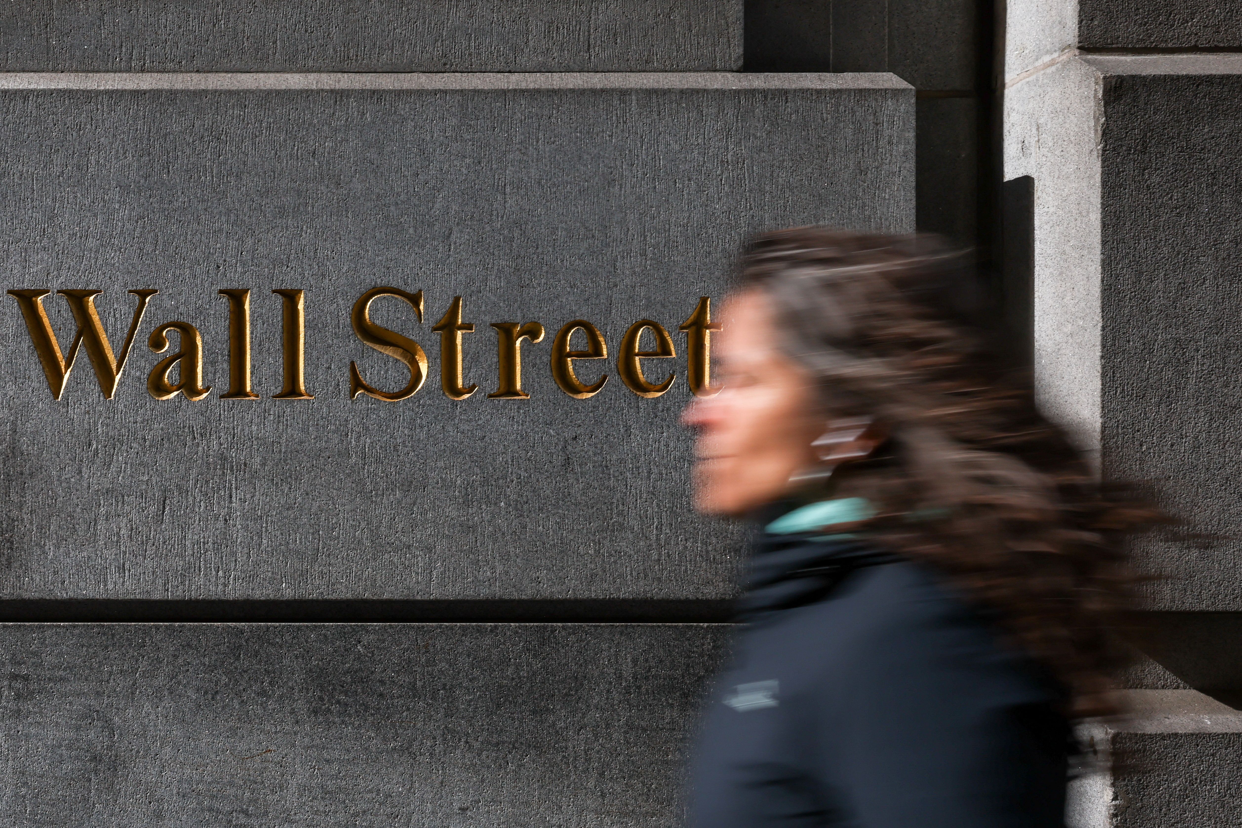 A woman walks past the Wall Street sign in New York City. 