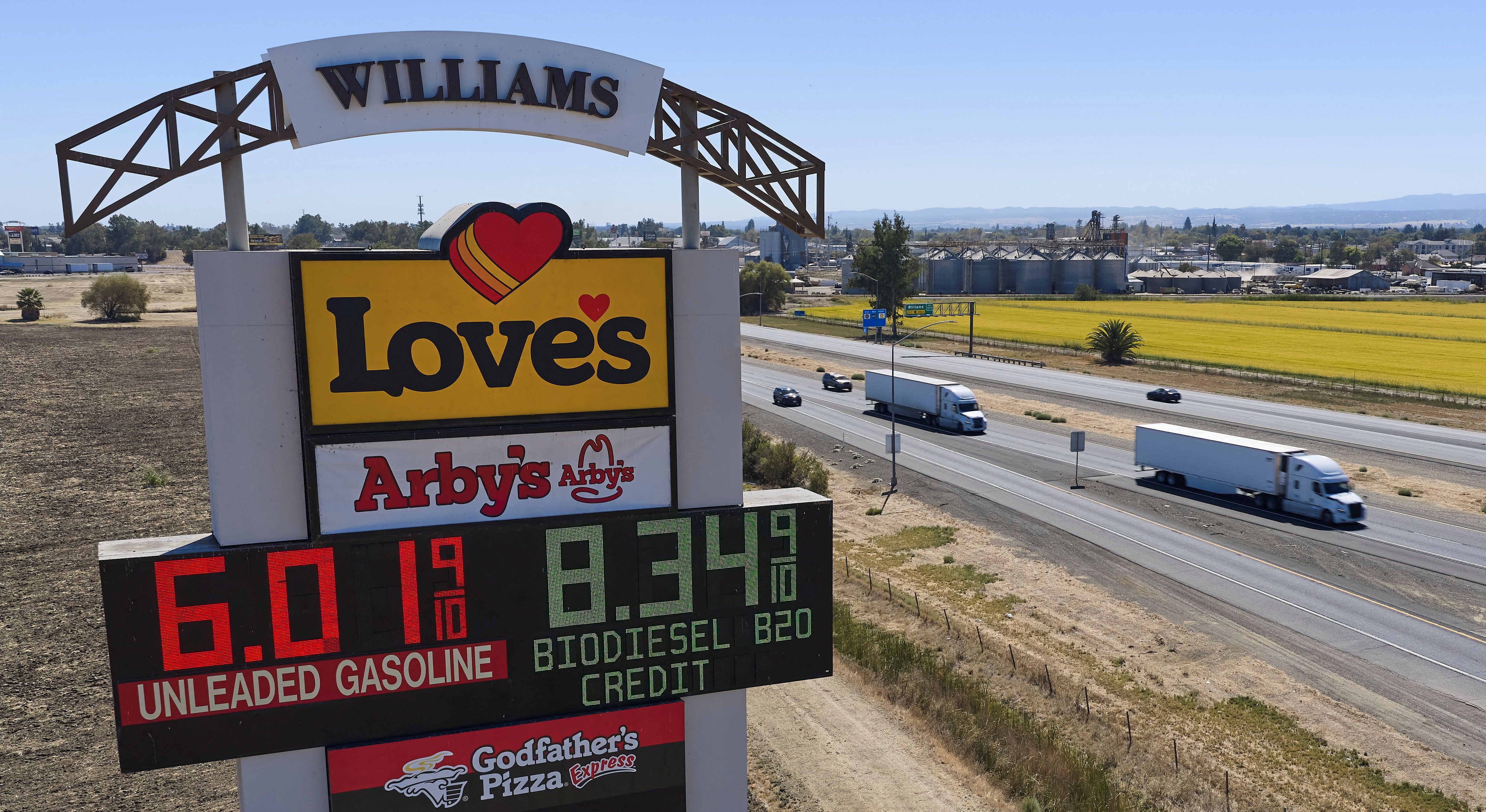 Semis drive past a sign advertising gas and diesel prices along Interstate 5 in Williams, California