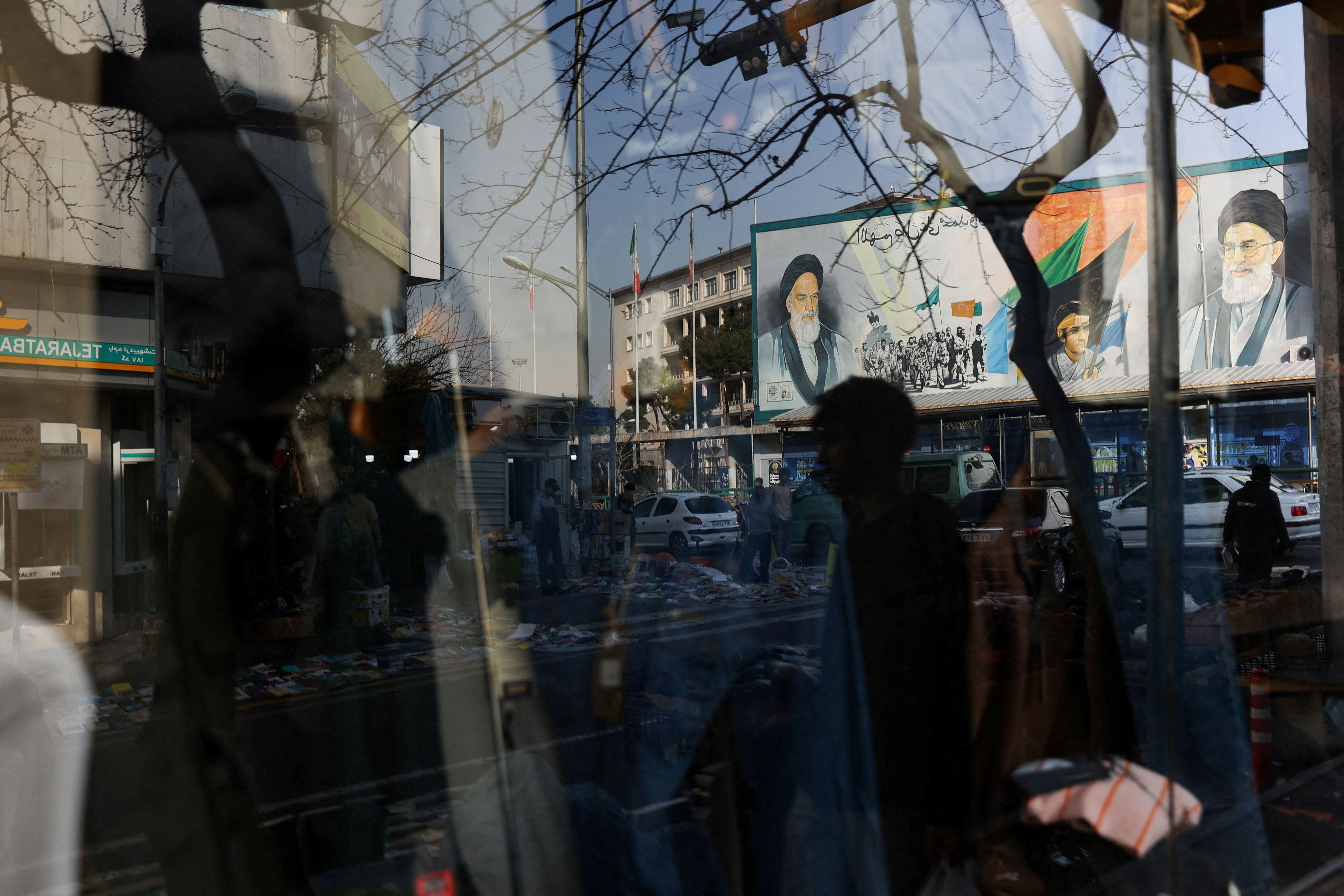 A sign with a depiction of Iran’s supreme leader is reflected in a shop window in Tehran