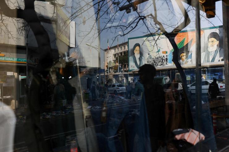 A sign with a depiction of Iran’s supreme leader is reflected in a shop window in Tehran