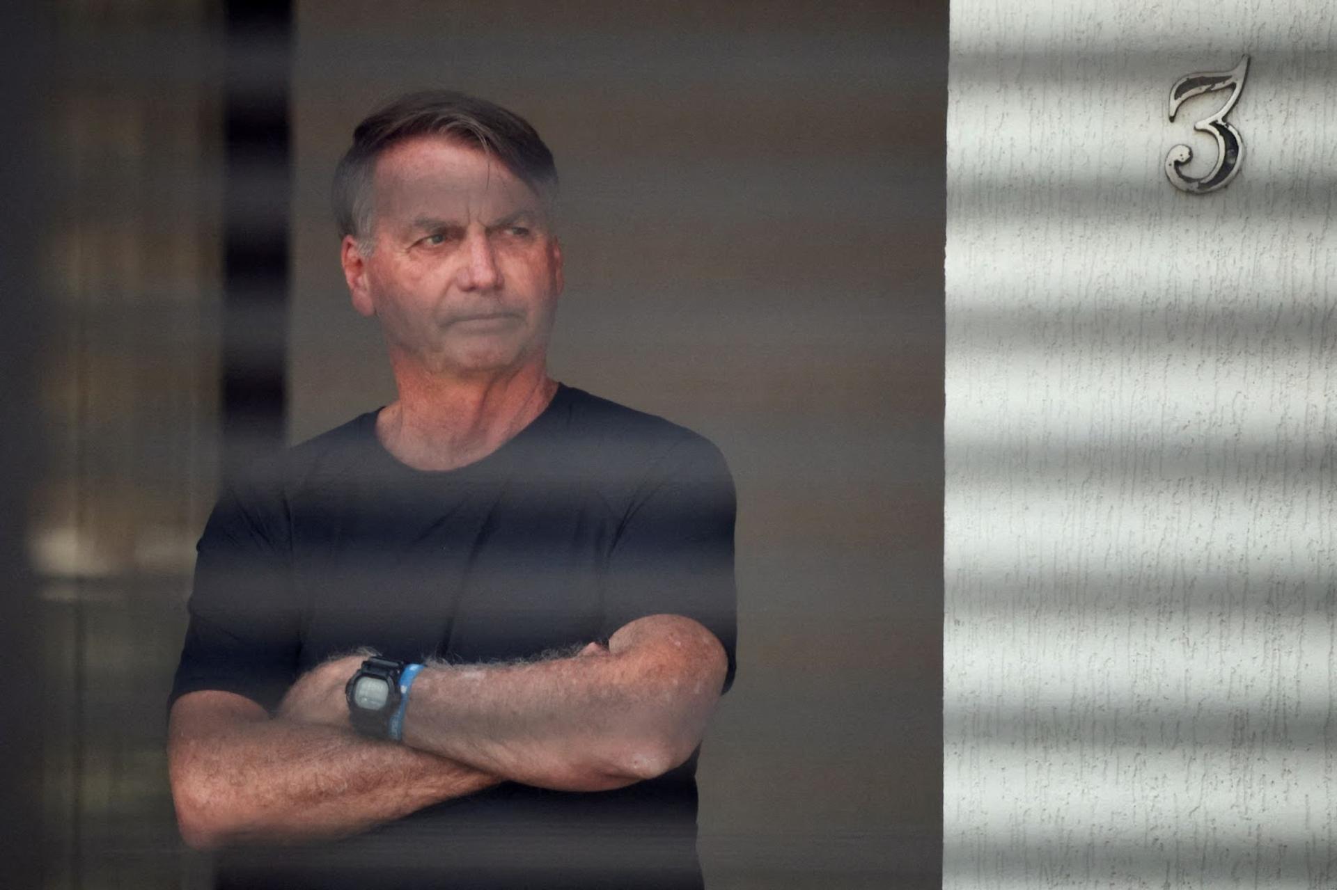 Brazil’s former President Jair Bolsonaro stands at his home while under house arrest. 